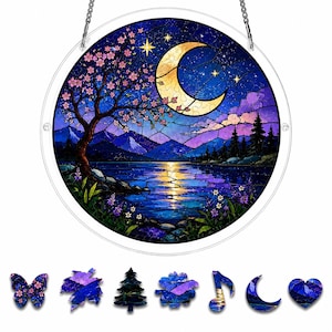Peut inclure: Un capteur de soleil circulaire en vitrail représentant un paysage nocturne avec un croissant de lune, des montagnes, un lac et un arbre en fleurs. En dessous, sept petites pièces de puzzle aux formes distinctes, dont un papillon, une feuille, un arbre et un cœur.