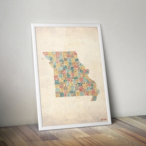 May include: A vintage-style print of the state of Missouri, USA, with the names of all the counties in the state arranged to form the shape of the state. The print is in a white frame and has a beige background.