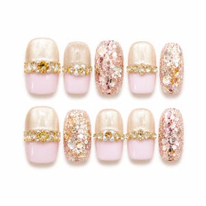 Puede incluir: Un juego de diez uñas postizas con una combinación de tonos base rosa claro y champán brillante. Algunas uñas están totalmente cubiertas de purpurina en oro rosa y plata, mientras que otras presentan bandas horizontales de cristales y perlas.