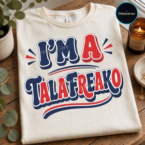 Op de afbeelding: Een crèmekleurig T-shirt met korte mouwen en de tekst I'M A TALAFREAKO in een vet retro lettertype. De letters wisselen af tussen marineblauw en rood, voorzien van een dikke witte omlijning en een subtiel slagschaduweffect.