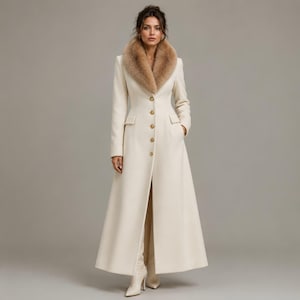 Puede incluir: Un abrigo largo de color marfil con cuello de piel y botones dorados. El abrigo tiene un corte entallado, bolsillos y una abertura alta en la parte delantera. La modelo lleva botas marfil a juego. Este elegante abrigo es adecuado para ocasiones formales.