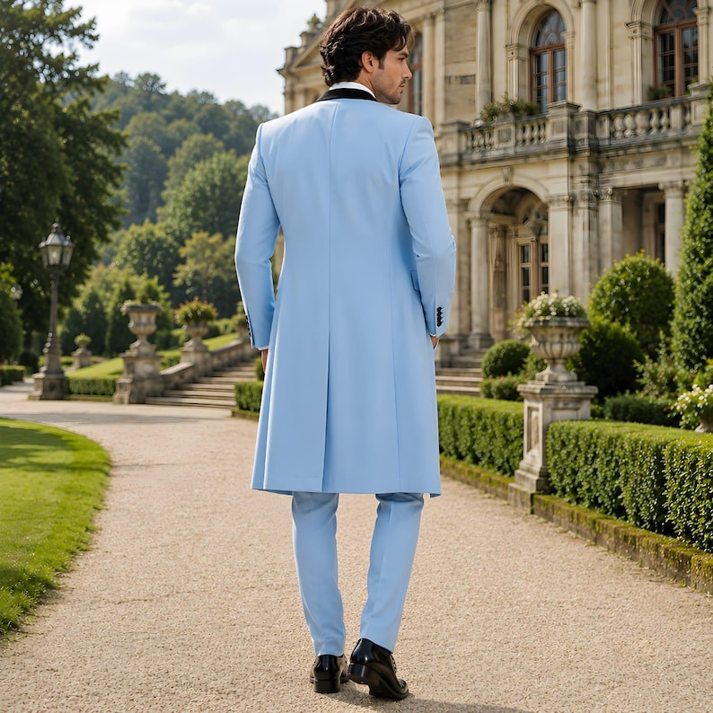 May include: A light blue suit with a long coat, black lapels, and matching pants. The suit is worn with a white shirt and black shoes. The coat has a pleated back. The suit is worn outdoors on a stone path.