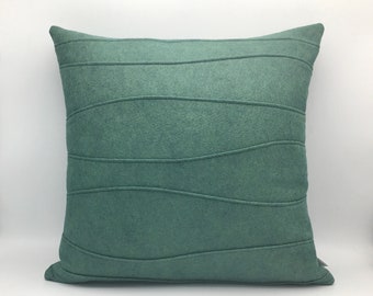 May include: A teal blue throw pillow with a wavy, quilted design. The pillow is made of a soft, textured fabric.