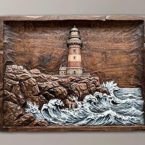 May include: A rectangular wooden wall carving featuring a detailed lighthouse standing on a rocky cliffside. The scene depicts crashing white waves against the dark brown textured rocks, with the lighthouse tower painted in shades of tan and red.