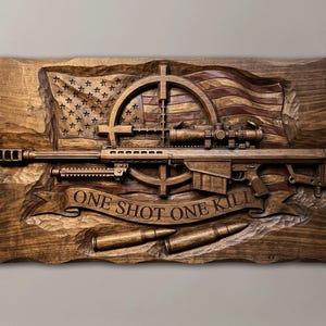Puede incluir: Una placa de pared rectangular de madera con una bandera estadounidense tallada de fondo, un rifle de francotirador central con mira y bípode, una retícula de mira, dos casquillos de bala en la parte inferior y una cinta con el texto ONE SHOT ONE KILL.