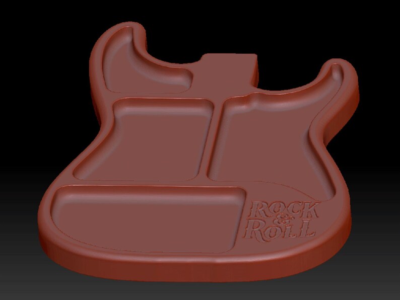May include: A brown, guitar-shaped tray with three recessed compartments. The tray features a smooth, molded surface with the embossed text "ROCK & ROLL" located in the lower right section, following the contour of the guitar body shape.