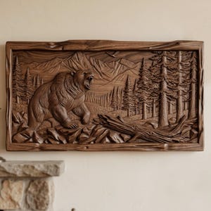 Puede incluir: Tallado en relieve de madera detallado de un oso en una escena forestal. El oso está rugiendo, con montañas y árboles en el fondo. La obra de arte está enmarcada en un borde de madera rústico, mostrando un tema natural y al aire libre.