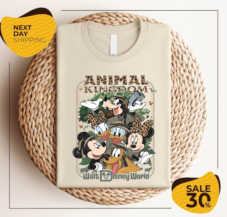 a t-shirt with a Disney-themed graphic design, including Mickey Mouse, Minnie Mouse, Donald Duck, and Goofy. The t-shirt is displayed on a woven basket, and there are two yellow sale signs indicating a 30% discount.