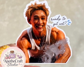 May include: A die-cut sticker featuring a person with short, light brown hair wearing a white tank top, smiling while splashing water. The text "ready to get wet?" appears in a script font next to the person, accompanied by blue water droplet icons.