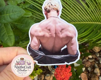 May include: A die-cut sticker featuring a muscular person viewed from the back with short blonde hair and a thin chain necklace, wearing a black leather jacket draped off the shoulders. A small circular logo sticker reads ApotheCraft Studio.