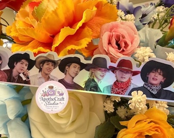 May include: A long, die-cut sticker featuring seven individuals wearing cowboy hats, arranged in a horizontal row. The sticker has a holographic finish and includes a circular logo with the text ApotheCraft Studio Crafted with a dose of joy.