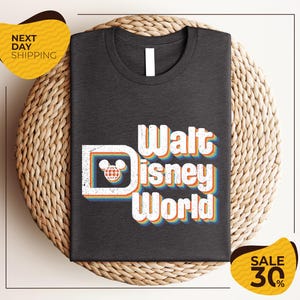 A black t-shirt with the text "Walt Disney World" printed on it, along with a Mickey Mouse logo. The t-shirt is displayed on a woven basket, and there are two yellow price tags in the image.