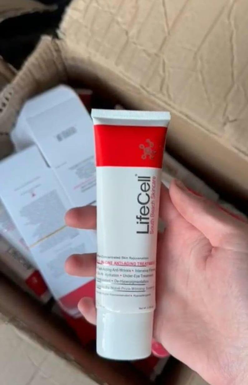 K&ouml;nnte beinhalten: Eine wei&szlig;e Tube mit LifeCell South Beach Skincare Anti-Aging-Behandlung mit rotem Deckel. Die Tube wird in der Hand einer Person gehalten. Das Produkt ist als konzentrierte Hautverj&uuml;ngungsbehandlung gekennzeichnet.