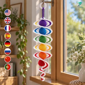 May include: A hanging crochet mobile featuring a vertical spiral structure in white yarn, interspersed with six spherical, textured crochet balls in a rainbow gradient of purple, blue, green, yellow, orange, and red, suspended by a loop.