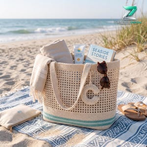 Può includere: Una borsa tote in crochet beige con motivo a griglia, una striscia turchese alla base e un ciondolo a forma di lettera C. All'interno ci sono un asciugamano beige, un tubetto di crema solare e un libro intitolato Seaside Stories.
