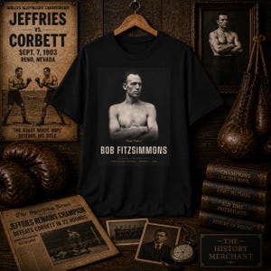 Könnte beinhalten: Ein schwarzes T-Shirt mit einem zentrierten, einfarbigen Porträt des Boxers Bob Fitzsimmons mit verschränkten Armen. Unter dem Porträt steht der Text "Ruby Robert" und "BOB FITZSIMMONS" in einer Vintage-Schriftart auf dunklem Grund.