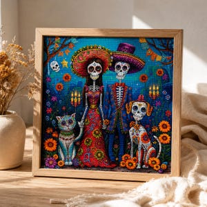 May include: A framed diamond painting featuring two skeleton figures in traditional attire, a skeleton cat, and a skeleton dog. The scene is set against a dark blue background with orange marigold flowers, lit candles, and colorful festive banners.