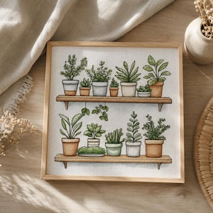 May include: A square framed cross-stitch embroidery featuring two wooden shelves holding various potted green plants. The plants are displayed in a mix of terracotta, white, and light grey pots, showcasing a variety of leaf shapes and sizes.
