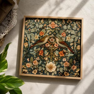 Può includere: Opera d'arte quadrata incorniciata con un elaborato motivo floreale e di uccelli. L'opera presenta due uccelli appollaiati su un ramo, circondati da fiori nei toni dell'arancione, del verde e del crema. La cornice è in legno chiaro.