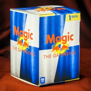 May include: A rectangular cardboard box containing a Magic The Gathering card deck. The packaging features a blue and silver design with water droplets, the Magic The Gathering logo, two red bulls, and a yellow label indicating 1 deck and 100 cards.
