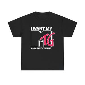 May include: Black t-shirt with the text "I WANT MY MTG MAGIC THE GATHERING" in white and pink. The design features a stylized "MTG" logo, reminiscent of a popular music television channel.