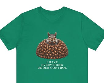 May include: A kelly green t-shirt featuring a graphic of a squirrel peeking out from a large pile of brown acorns. Below the squirrel, the text "I HAVE EVERYTHING UNDER CONTROL" is printed in white capital letters in a clean, serif font.