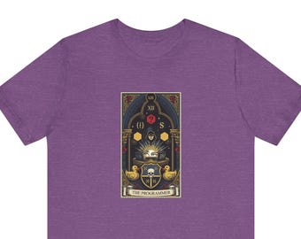 May include: A heather purple t-shirt featuring a graphic print of a tarot card titled THE PROGRAMMER. The design depicts a hooded figure at a desk with laptops, flanked by two yellow rubber ducks, a skull shield, and various coding symbols.