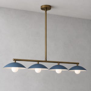 May include: A linear chandelier featuring a central brass rod and four matte blue dome-shaped shades. Each shade is equipped with a small, spherical white light bulb underneath, providing downward illumination from the horizontal metal fixture.