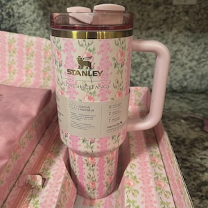 Pu&ograve; includere: Un bicchiere Stanley Loveshackfancy Flowstate rosa e floreale con manico. Il bicchiere ha un coperchio rosa e un motivo floreale con il logo Stanley. Il bicchiere &egrave; nella sua confezione originale, che ha anche un motivo floreale.
