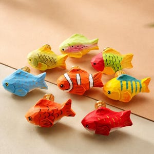 May include: A collection of eight small, hand-carved wooden fish drawer knobs, each painted in vibrant colors including yellow, blue, orange, red, and green, featuring distinct scale patterns and attached to small brass-colored metal hardware bases.
