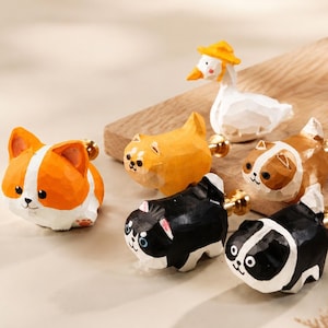May include: A collection of six hand-carved wooden drawer knobs featuring animal shapes including a corgi, a goose wearing a yellow hat, a brown and white cat, a black and white cat, and a solid orange cat, each with a gold-toned metal mounting post.