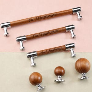Puede incluir: Tres tiradores de armario de madera marrón con extremos de metal cromado, cada uno grabado con el texto No. 1Hardware, y tres pomos de armario redondos de madera con bases cromadas, dispuestos para mostrar diferentes tamaños de herrajes.