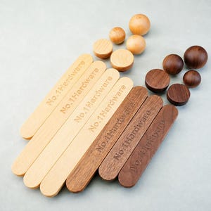 May include: A collection of light and dark wood hardware pieces, including four elongated rectangular strips and several spherical knobs. Each strip is engraved with the text No.1 Hardware. The set features natural wood grain textures.
