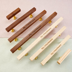 May include: A collection of six linear cabinet pulls arranged diagonally. Three pulls are made of dark brown wood and three are made of light beige wood. Each pull features gold-toned metal mounting posts and the text No.1Hardware engraved.