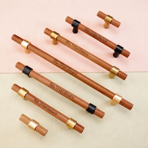 May include: A collection of cylindrical wooden cabinet pulls and knobs featuring metallic accents in gold and black finishes. Each wooden handle is engraved with the text No.1Hardware, showcasing a variety of lengths and hardware configurations.