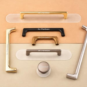 Könnte beinhalten: Eine Sammlung von Möbelgriffen aus Metall, bestehend aus verschiedenen Schubladengriffen und einem runden Knopf. Die Stücke haben Oberflächen in Gold, Mattschwarz, gebürsteter Bronze und Silber. Jeder Artikel trägt die Gravur No.1Hardware.
