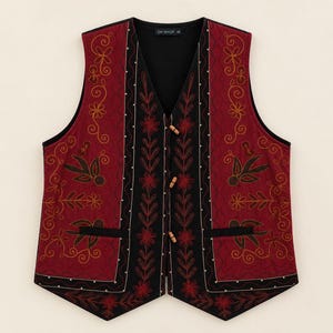 Peut inclure: Un gilet sans manches en tissu matelassé rouge foncé avec des broderies florales dorées et sombres. Le vêtement présente un panneau central noir avec des motifs floraux rouges, trois fermetures à bascule en bois et une étiquette DW-SHOP.