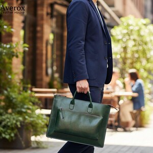 Pode incluir: Uma pasta de couro verde com um bolso frontal a condizer e al&ccedil;as superiores &eacute; transportada por uma pessoa que usa um fato azul marinho. A pasta tem um acabamento brilhante. A marca "Averox Leather House" &eacute; vis&iacute;vel no canto superior esquerdo.