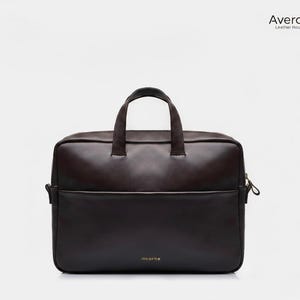 Könnte beinhalten: Eine dunkelbraune Lederaktentasche mit einem oberen Griff und einer Vordertasche. Die Tasche hat einen Reißverschluss und der Markenname "Averox Leather House" ist in der oberen rechten Ecke sichtbar. Das Wort "incarne" ist auf der Unterseite der Tasche aufgedruckt.