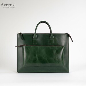 Pode incluir: Uma pasta de couro verde escuro com uma al&ccedil;a superior e um bolso frontal. A bolsa tem fecho de z&iacute;per e um design minimalista. A marca "Averox Leather House" est&aacute; no canto superior esquerdo.