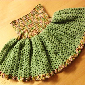 Puede incluir: Una falda de crochet verde con una cintura de punto multicolor. La falda tiene un borde festoneado con un ribete rosa, verde y marrón.