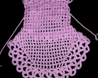 May include: A handmade, light purple crochet pouch with a scalloped edge. The pouch is open at the top and has a drawstring closure. The crochet work features an open, lacy design. The background is black.