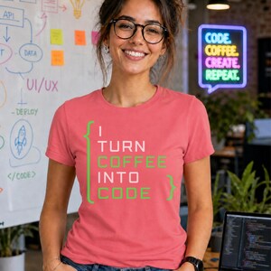May include: A coral-colored short-sleeve t-shirt featuring the text "I TURN COFFEE INTO CODE" in white and lime green lettering, framed by two large curly brackets. The shirt has a crew neckline and a standard fit, made of a solid fabric.