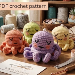 Peut inclure: Plusieurs porte-clés pieuvres crochetés aux couleurs vives : orange, vert, jaune et violet. Chaque pieuvre a un visage souriant et est attachée à un porte-clés argenté. L'image comprend également un patron de crochet et des bobines de fil.