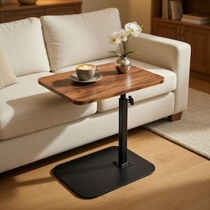 May include: A height-adjustable side table with a rectangular walnut-toned wooden top and a black metal base. On the table sits a ceramic mug filled with coffee and a small silver vase containing white orchid flowers with green stems.