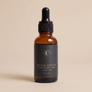 May include: A brown glass bottle of Moon Sister Radiance Renewing Oil Serum with a black label. The label features a sun and moon design and the text "Rosehip + Neroli". The bottle contains 1 fl oz of serum.