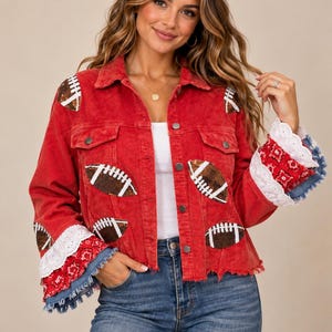 May include: A red corduroy jacket featuring sequined football patches on the front and sleeves. The cuffs are layered with white eyelet lace, red paisley fabric, and frayed denim edges. The jacket has a collar, button-down front, and chest pockets.