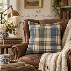 Harvest Tartan pillow cover styled on a vintage brown leather chair with cream knit throw, brass lamp, books and blue-and-white cottage decor.