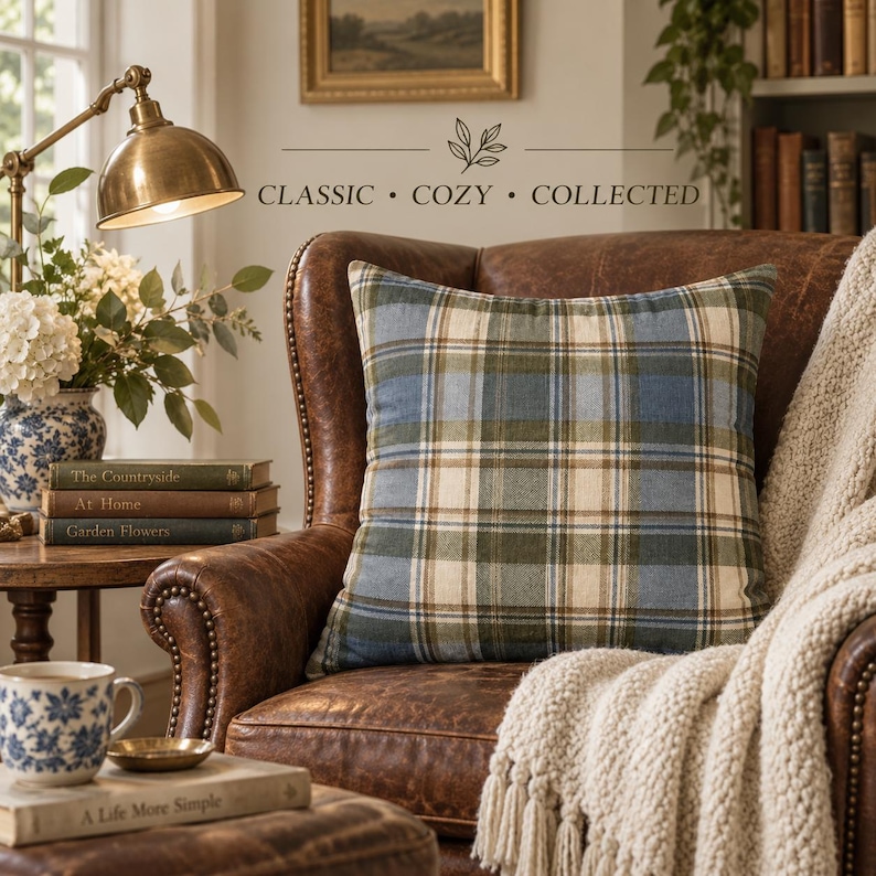 Harvest Tartan pillow cover styled on a vintage brown leather chair with cream knit throw, brass lamp, books and blue-and-white cottage decor.