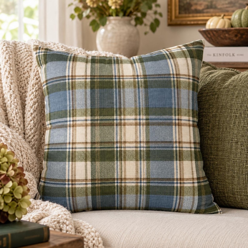 Blue and olive tartan pillow cover styled on a cream sofa with a cozy knit throw, olive accent pillow, hydrangeas, books and subtle autumn decor.